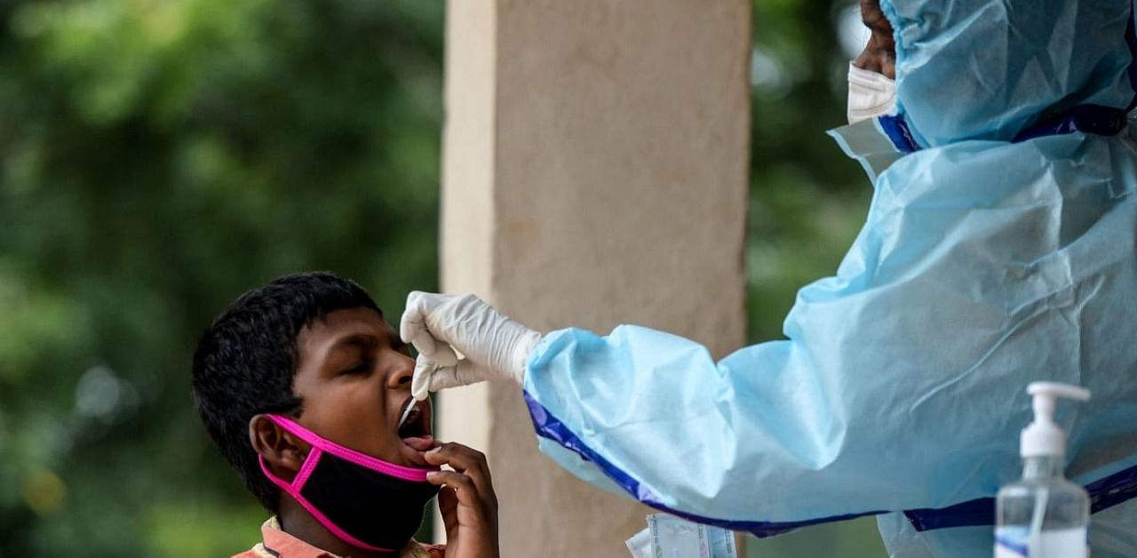 A health worker (R) collects a swab sample from a boy to test for the Covid-19 coronavirus at a community gym centre on the outskirts of Hyderabad on October 8, 2020. Credit: AFP Photo