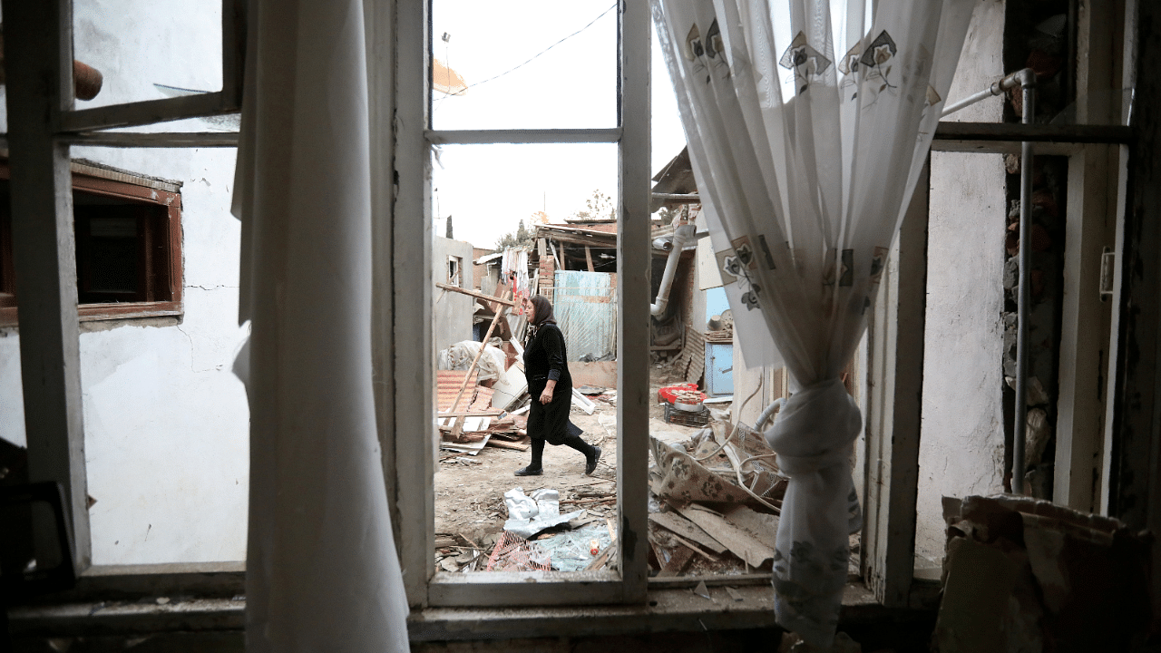 A woman walks past a house damaged by recent shelling during a military conflict over the breakaway region of Nagorno-Karabakh. Credits: Reuters Photo