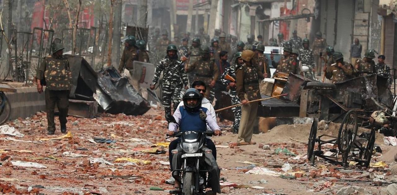 Men ride a motorcycle past security forces patrolling a street in a riot affected area after clashes erupted between people demonstrating for and against a new citizenship law in New Delhi, India, February 26, 2020. (Reuters)