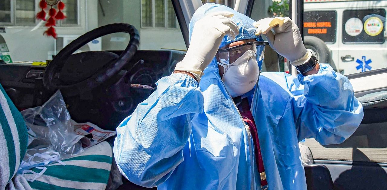 An ambulance driver, wearing protective suits, prepares to exit the Special Isolation Ward with novel coronavirus patients at Kochi Medical college, in Kerala. Credit: PTI Photo