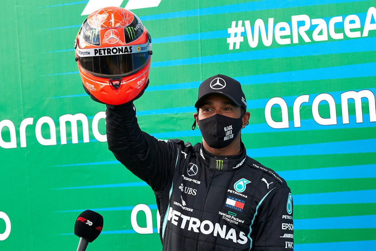 Mercedes' Lewis Hamilton poses with a red helmet from Mick Schumacher. Credit: Reuters