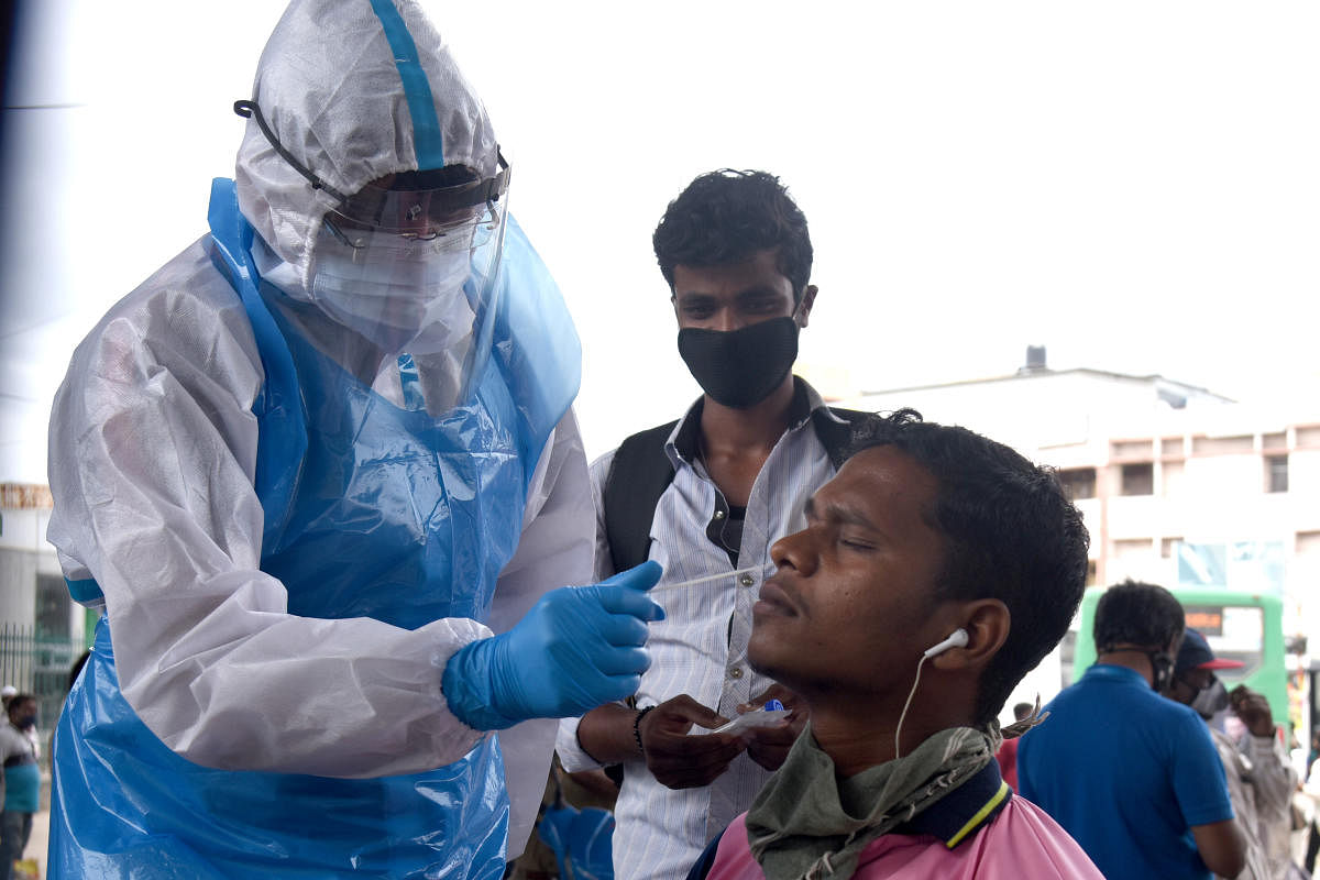 Health staff collecting nasal swab for corona virus test at Covid 19 lockdown unlock 05 norms in free checkup by BBMP at KR Market bus stand in Bengaluru. Credit: DH Photo/S K Dinesh