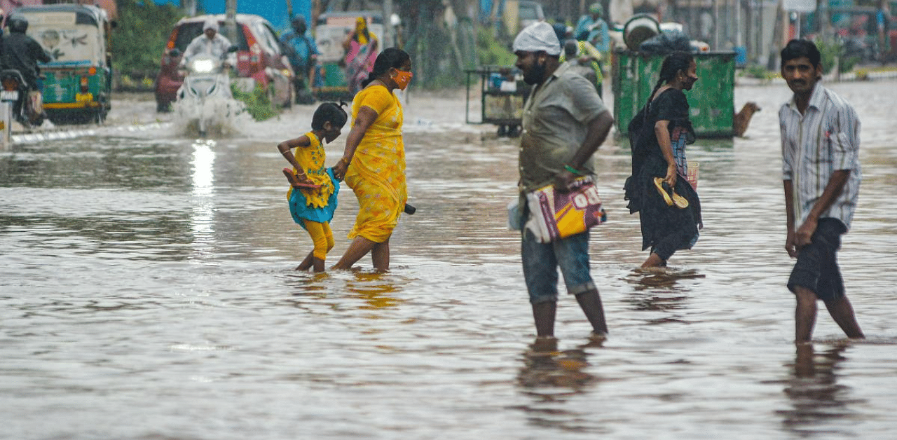 People wade through a waterlogged road during heavy rains, due to a deep depression in Bay of Bengal, in Vijayawada. Credit: PTI Photo