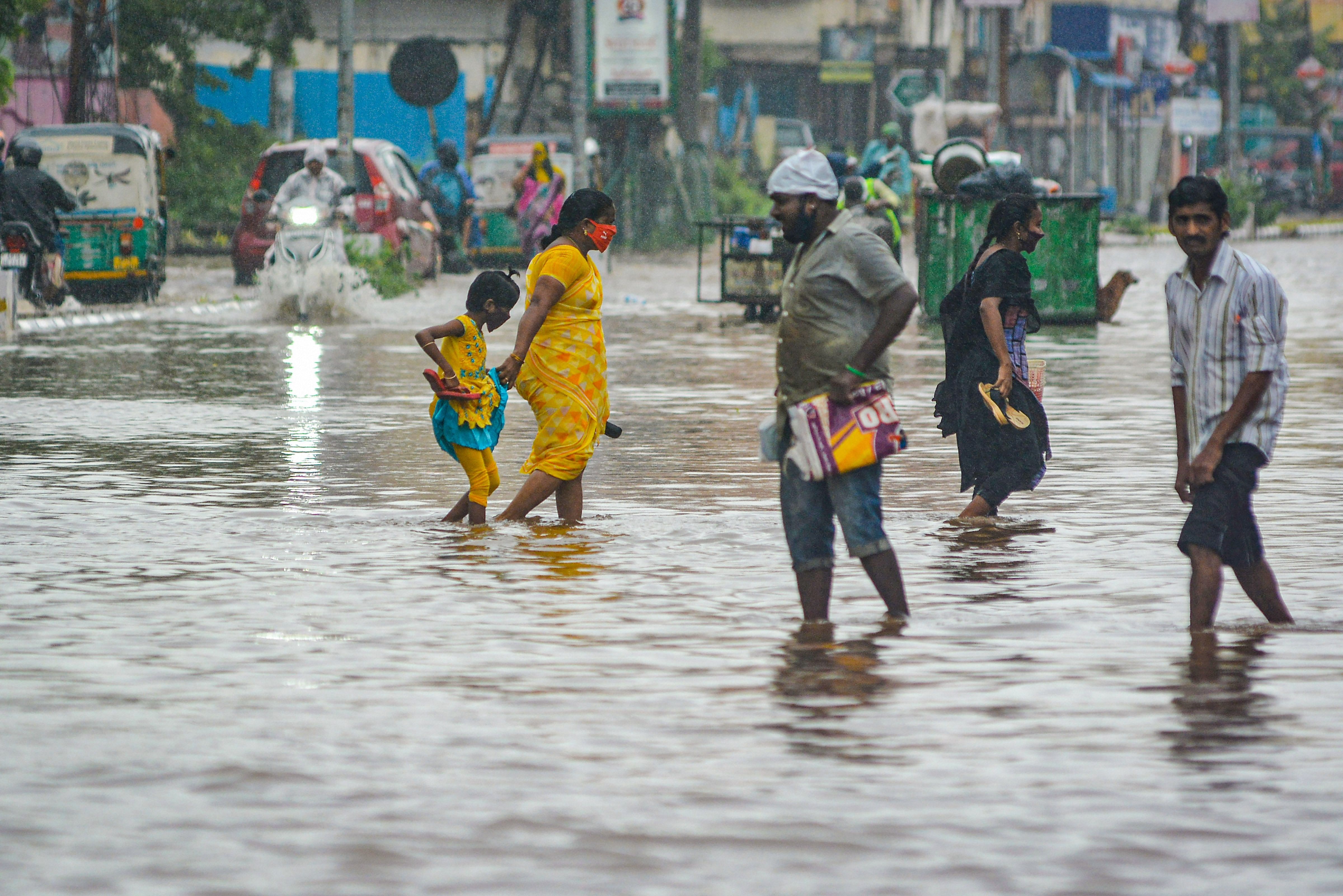 People wade through a waterlogged road during heavy rains, due to a deep depression in Bay of Bengal, in Vijayawada, Tuesday, Oct. 13, 2020. Credit: PTI Photo