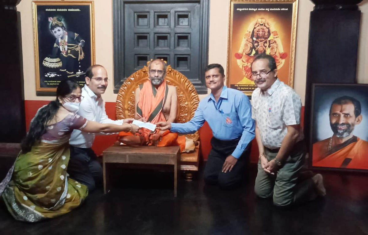 Alumni of the 1995 science batch of Adamaru Poornaprajna PU College handed over a cheque for Rs 11.68 lakh to Adamaru Mutt pontiff Eshapriya Theertha swami.