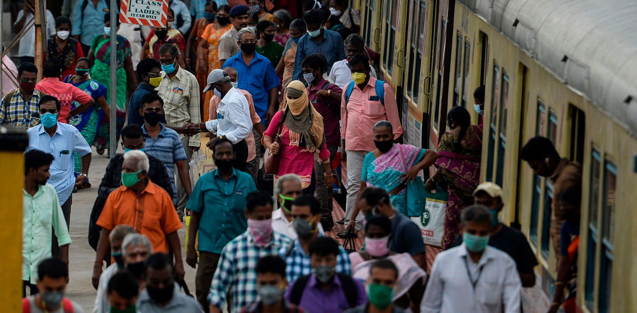 Commuters wearing facemasks to prevent the spread of the Covid-19 coronavirus walk along a platform at a train station in Chennai. Credit: AFP Photo