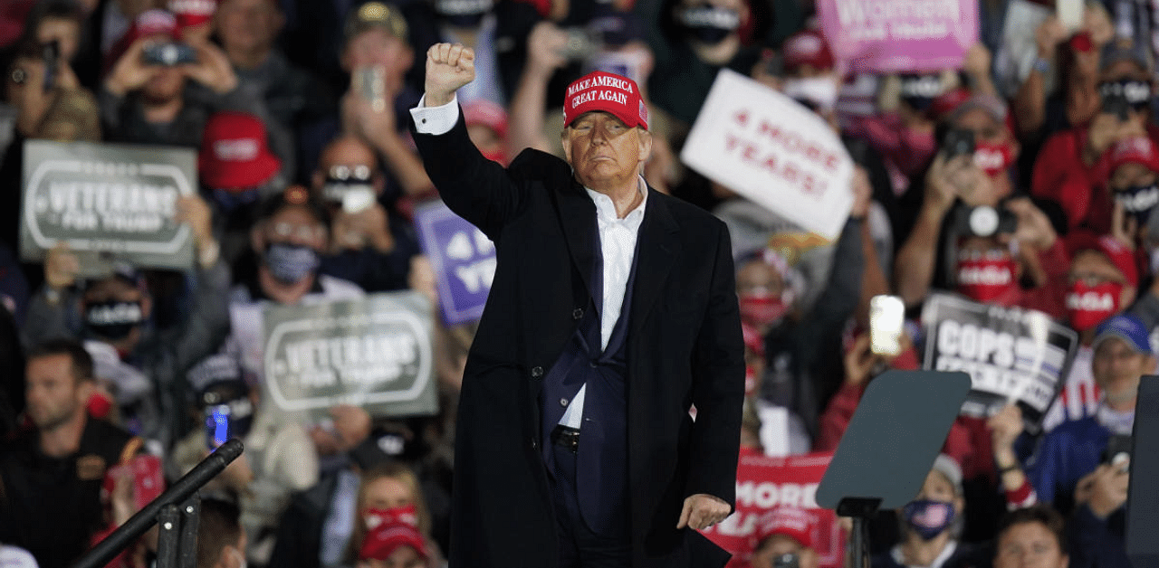 President Donald Trump pumps his fist at supporters after speaking at an airport campaign rally in Des Moines, Iowa. Credit: AP Photo