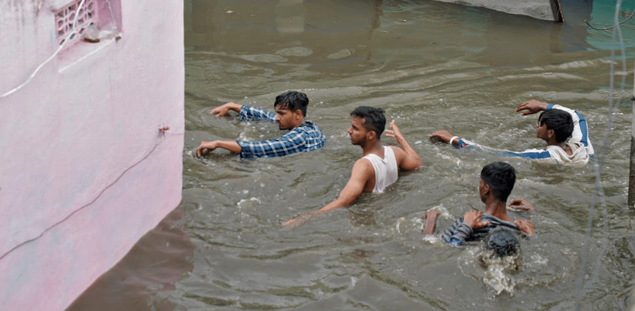 Residents wade through a waterlogged alley after heavy rainfall in Hyderabad, the capital of the southern state of Telangana, India, October 14, 2020. Credit: Reuters Photo