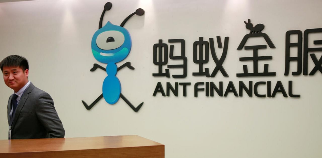 An employee stands next to the logo of Ant Financial Services Group. Credit: Reuters