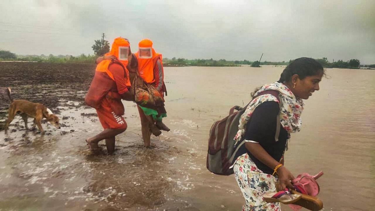 NDRF personnel carry out rescue operations to move locals to a safer place following heavy rain, in Kolegaon. Credit: PTI.