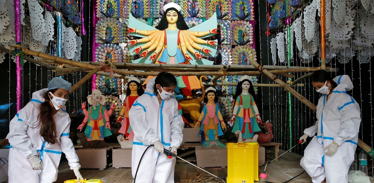 Women wearing personal protective equipment (PPE) sanitize a "pandal" or a temporary platform, ahead of Durga Puja festival, amidst the spread of the coronavirus disease. Credit: Reuters Photo