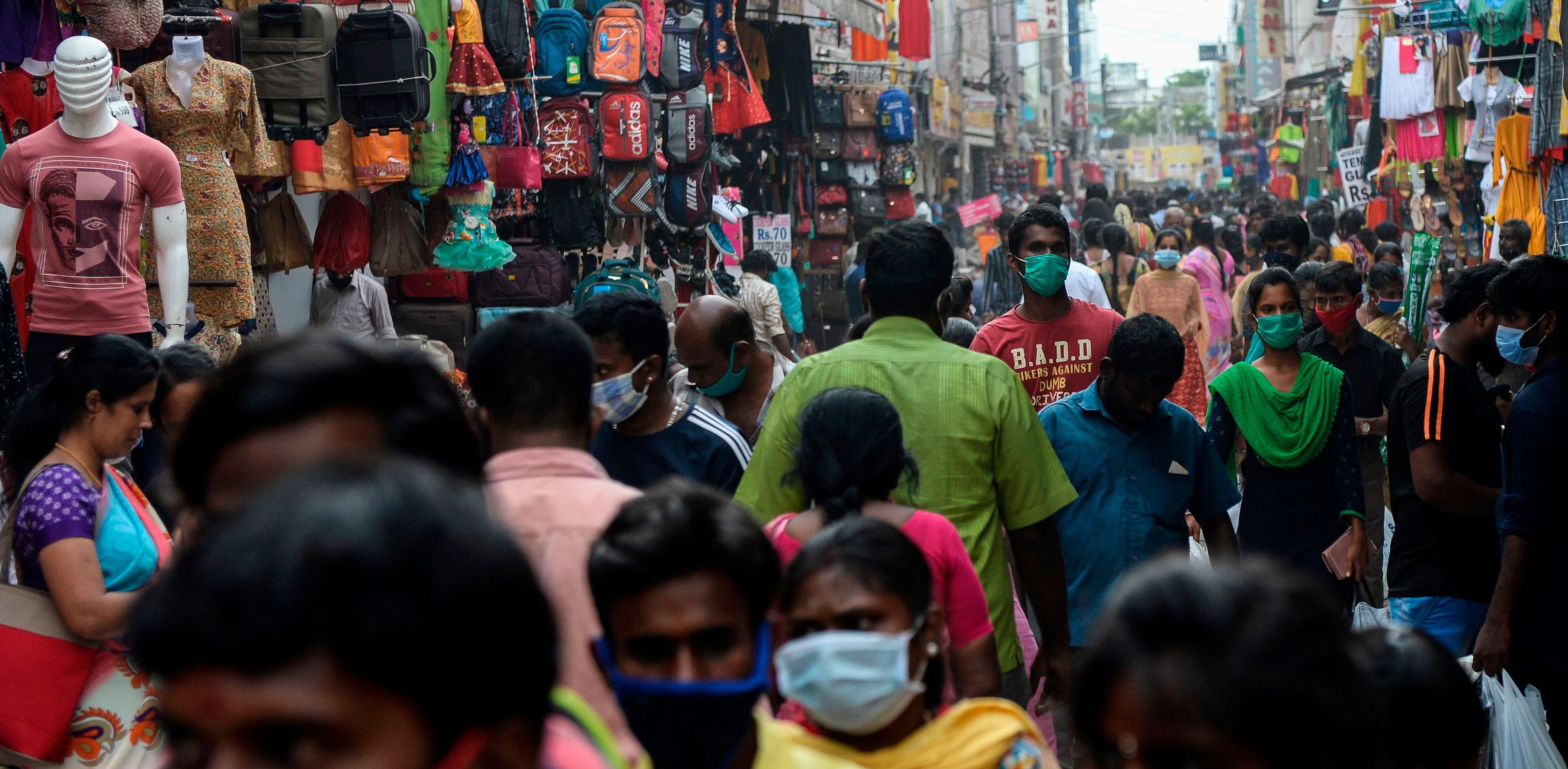People wearing facemasks to prevent the spread of the Covid-19 coronavirus walk along a commercial street in Chennai. Credit: AFP