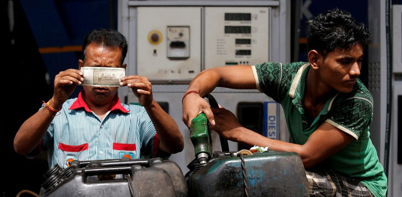 A worker checks a 500 Indian rupee note as a man fills diesel in containers at a fuel station in Kolkata, India. Credit: Reuters