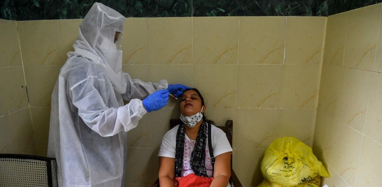 A health worker (L) takes a swab sample from a woman for a Covid-19 test. Credit: AFP