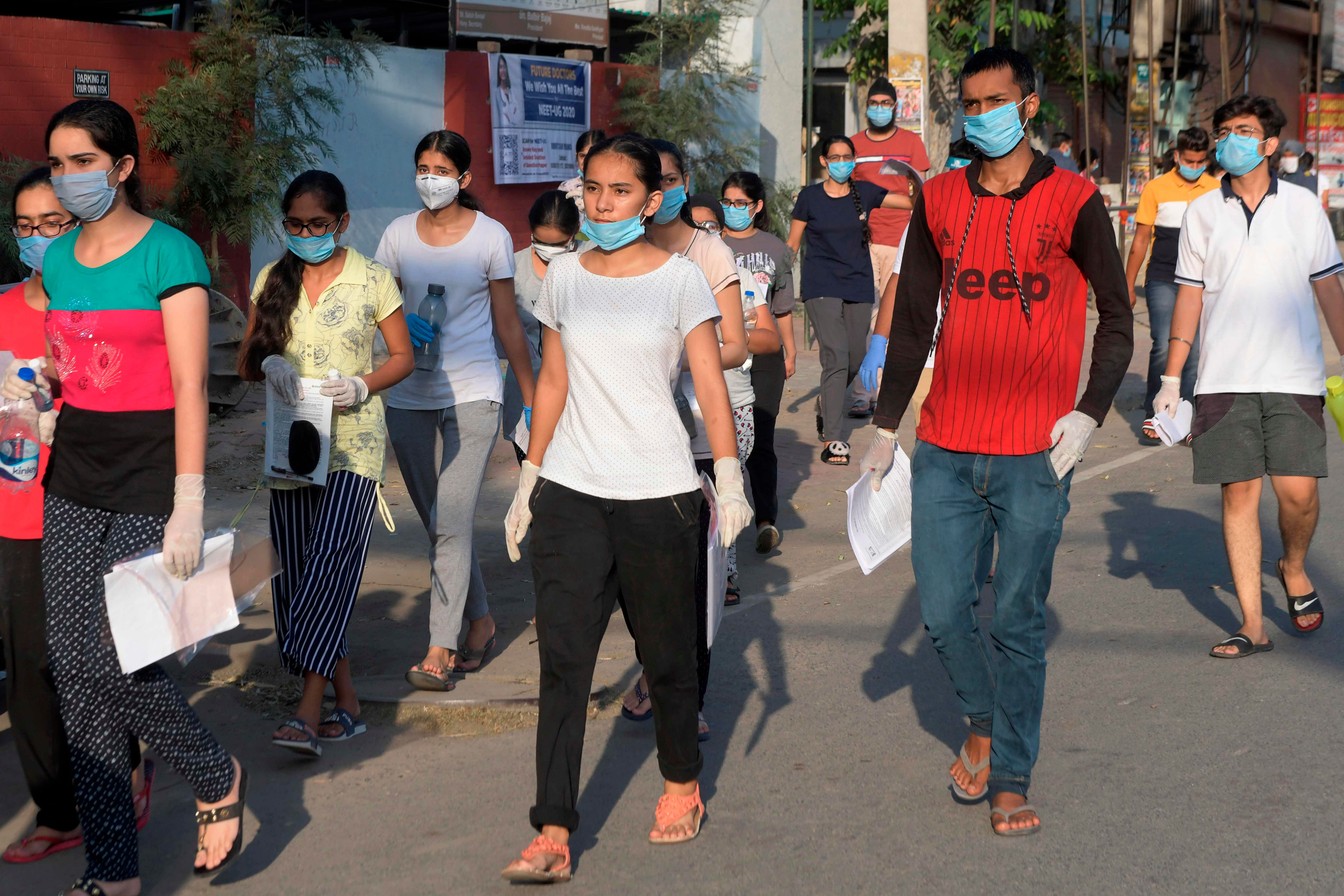 Students walk along a road as they come out from an examination centre after taking the National Eligibility Cum Entrance Test. Credits: AFP Photo