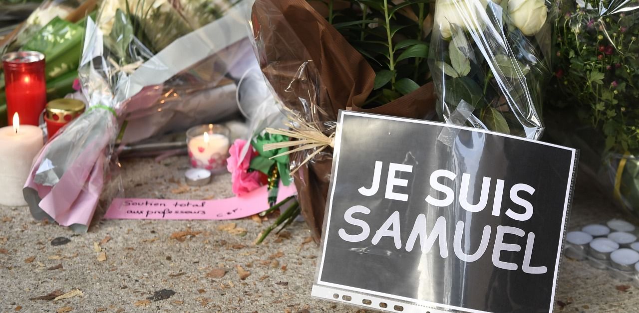 A photo shows flowers, candles, a message reading 'Total support to teachers' and a placard reading 'I am Samuel' at the entrance of a middle school in Conflans-Sainte-Honorine, 30 kms northwest of Paris. Credit: AFP Photo