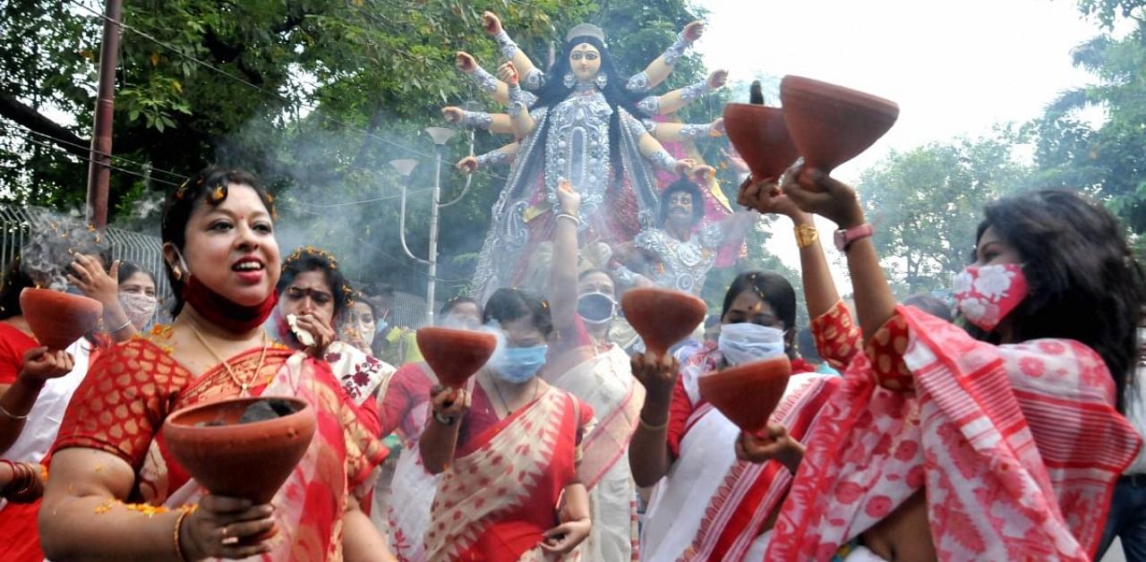 Women perform 'Dhunachi' dance on the arrival procession of Goddess Durga idol at their community puja pandal ahead of 'Durga Puja' festival, amid coronavirus pandemic, in Kolkata, Friday, Oct. 16, 2020. Credit: PTI Photo