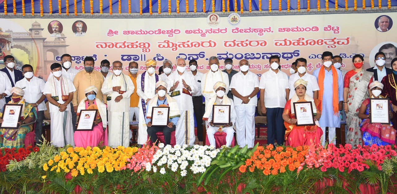 Covid warriors -- nurse P M Rukmini, ASHA volunteer Noor Jaan, civic worker Maragamma, social worker Ayub Ahamed, Police personnel P Kumar and Dr T R Naveen -- being felicitated during the inaugural function of Dasara, atop the Chamundi Hill, in Mysuru, on Saturday. Chief Minister B S Yediyurappa, Cooperation Minister S T Somasekhar and Agriculture Minister B C Patil are seen. Credit: DH Photo