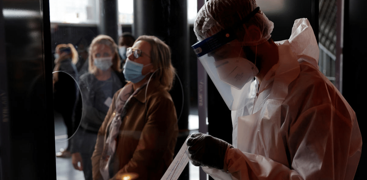 A health worker, wearing a protective suit and a face mask, prepares to administer a nasal swab to a patient in a temporary testing site for the coronavirus disease (COVID-19) at the Zenith Arena in Lille, France. Credit: Reuters Photo
