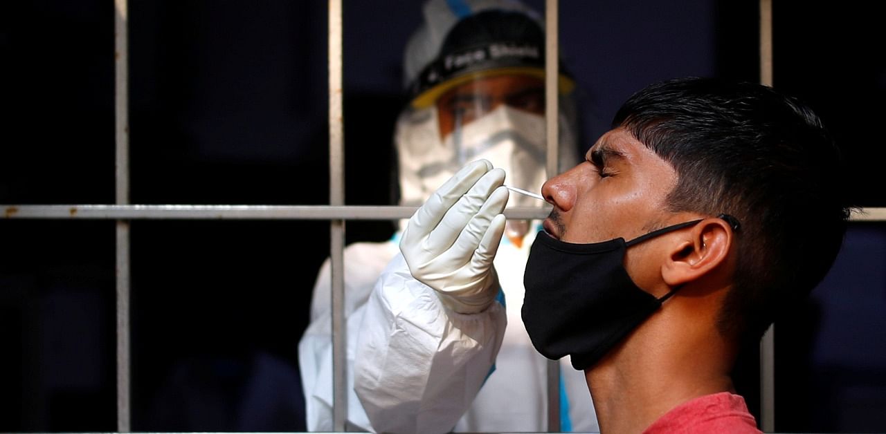 A man reacts as a healthcare worker collects a swab sample amidst the spread of the coronavirus disease. Credit: Reuters Photo