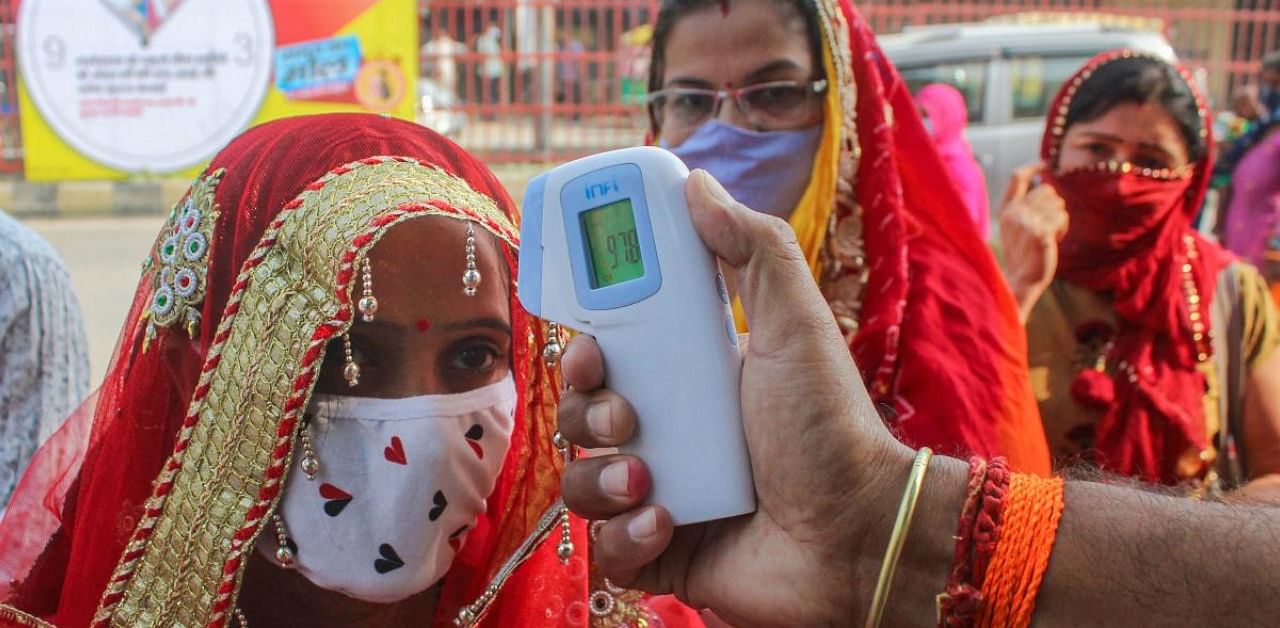 Devotees undergo thermal screening as they arrive to offer prayers at Sheetla Mata Mandir on the first day of Navratri festival, in Gurugram. Credit: PTI