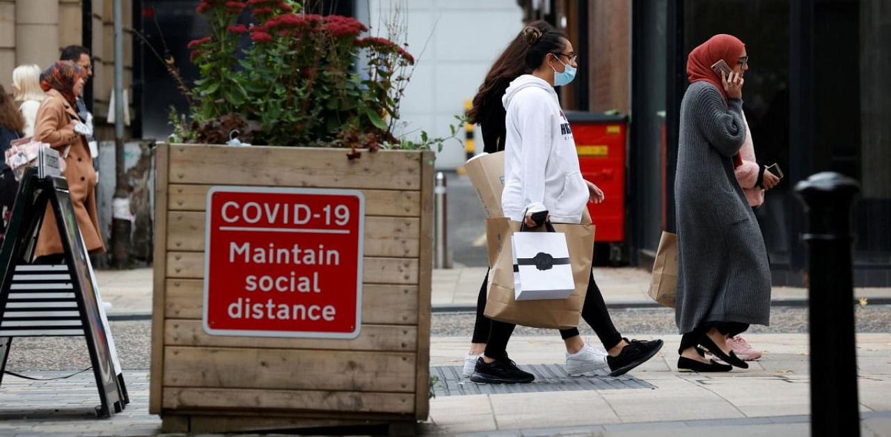 People walk pass a sign with safety measures at the city centre amidst the outbreak of the coronavirus disease in Britain. Credit: Reuters