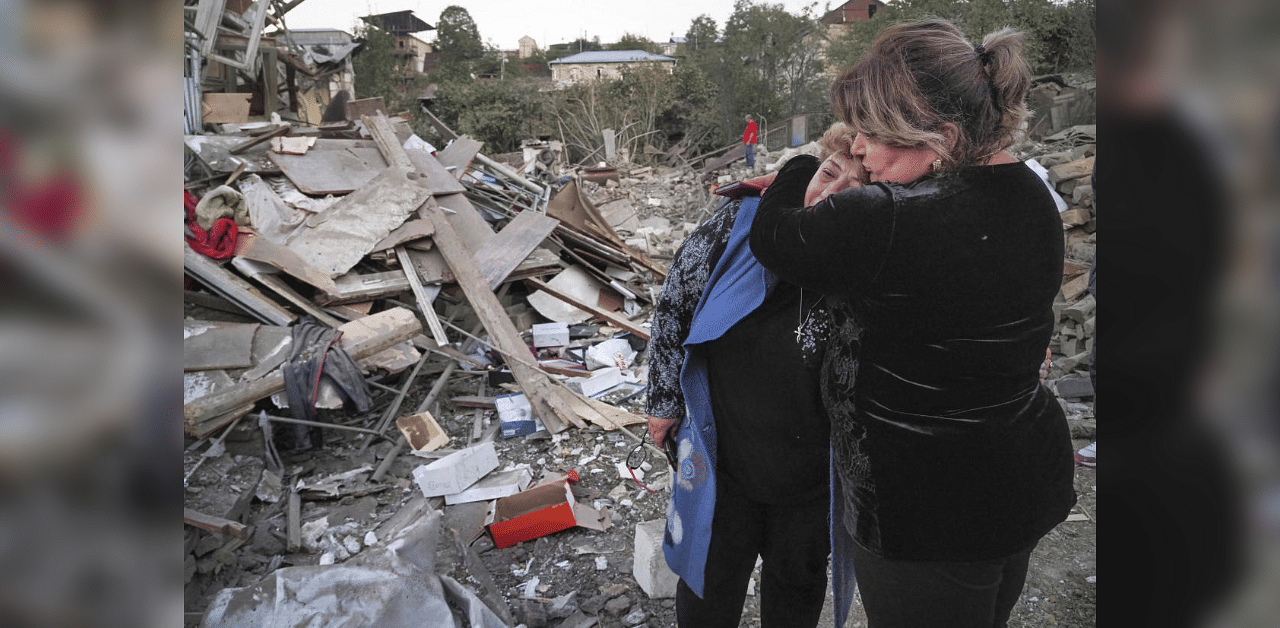 A neighbour comforts home owner, Lida Sarksyan, left, near her house destroyed by shelling from Azerbaijan's artillery during a military conflict in Stepanakert, the separatist region of Nagorno-Karabakh, Saturday, Oct. 17, 2020. Credit: AFP Photo