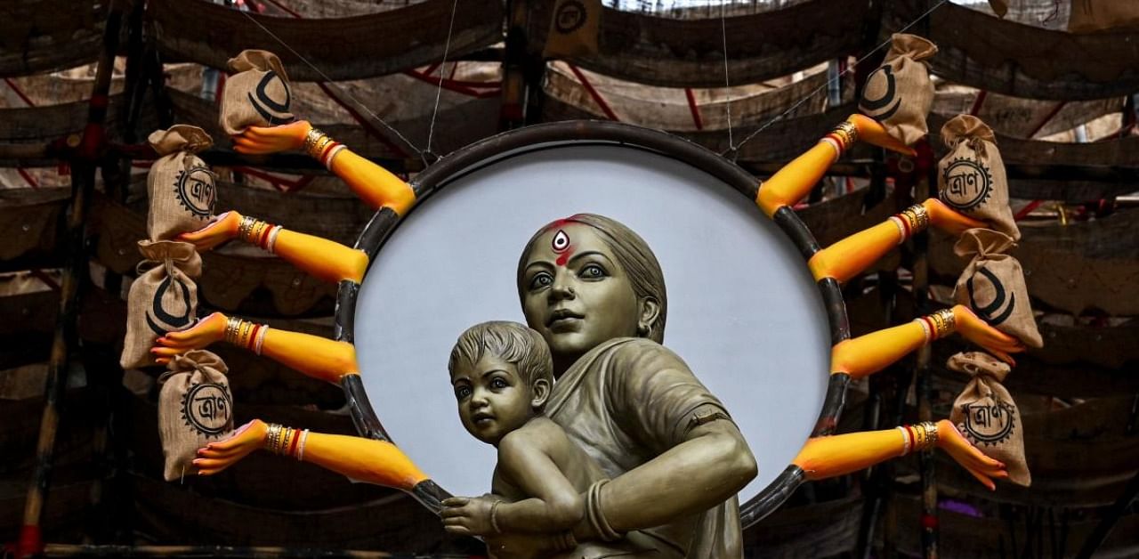 A model of a migrant mother symbolising Hindu Goddess Durga and holding a child is surrounded by relief material as a theme decoration to create awareness about the migrant labourers' social issues during the lockdown previously imposed due to the Covid-19 coronavirus pandemic, at a makeshift place for worship ahead of the Hindi festival 'Durga Puja' in Kolkata on October 17, 2020. Credit: AFP Photo