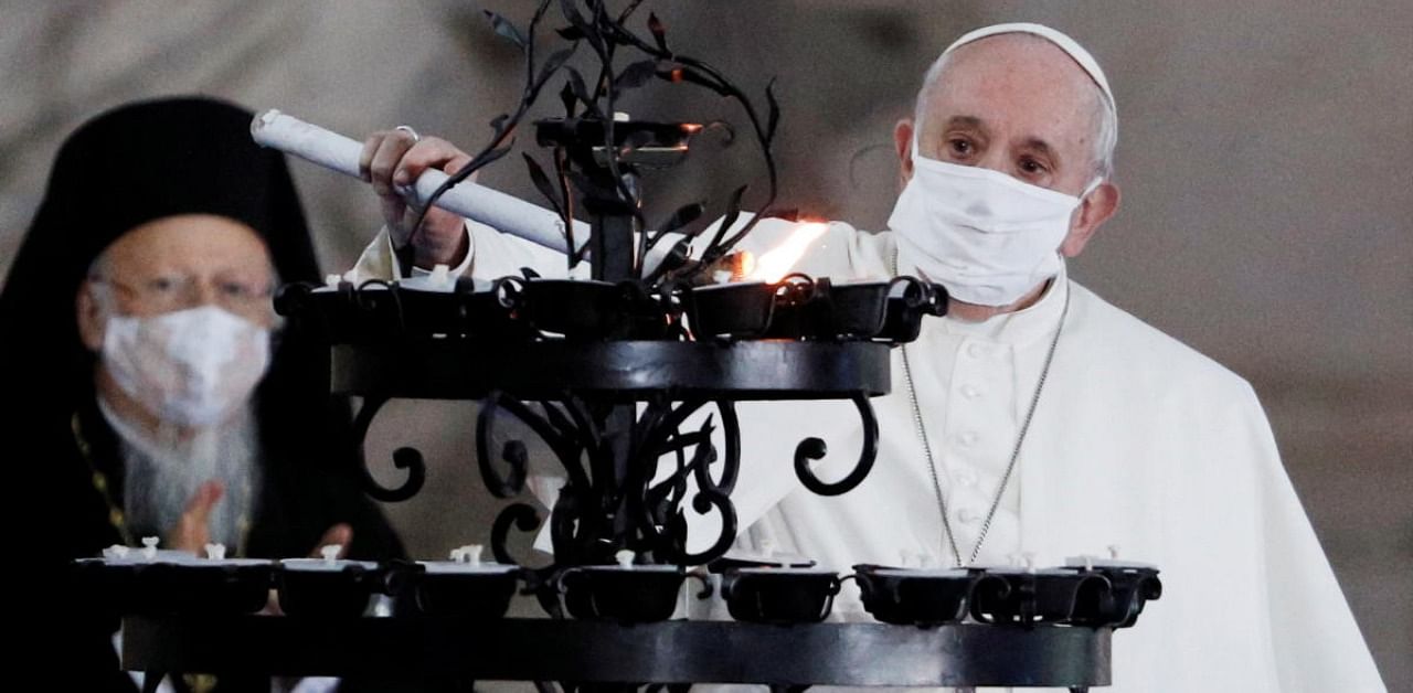 Pope Francis wearing a face mask lights a candle during a ceremony for peace with representatives from various religions in Campidoglio Square, in Rome. Credit: Reuters