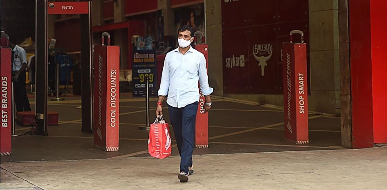 In this picture taken on October 19, 2020, a man carries bags as he leaves a shopping mall in Mumbai. Credit: AFP.