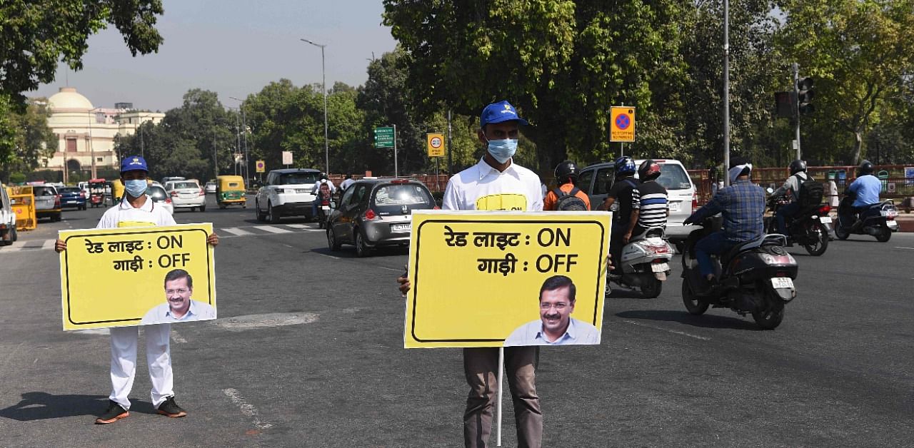 Civil defence volunteers hold placards on a busy road during an initiative taken by Delhi government asking commuters to switch-off the ignition of their vehicles at traffic red lights in order to control pollution levels near India Gate in New Delhi. Credit: AFP Photo