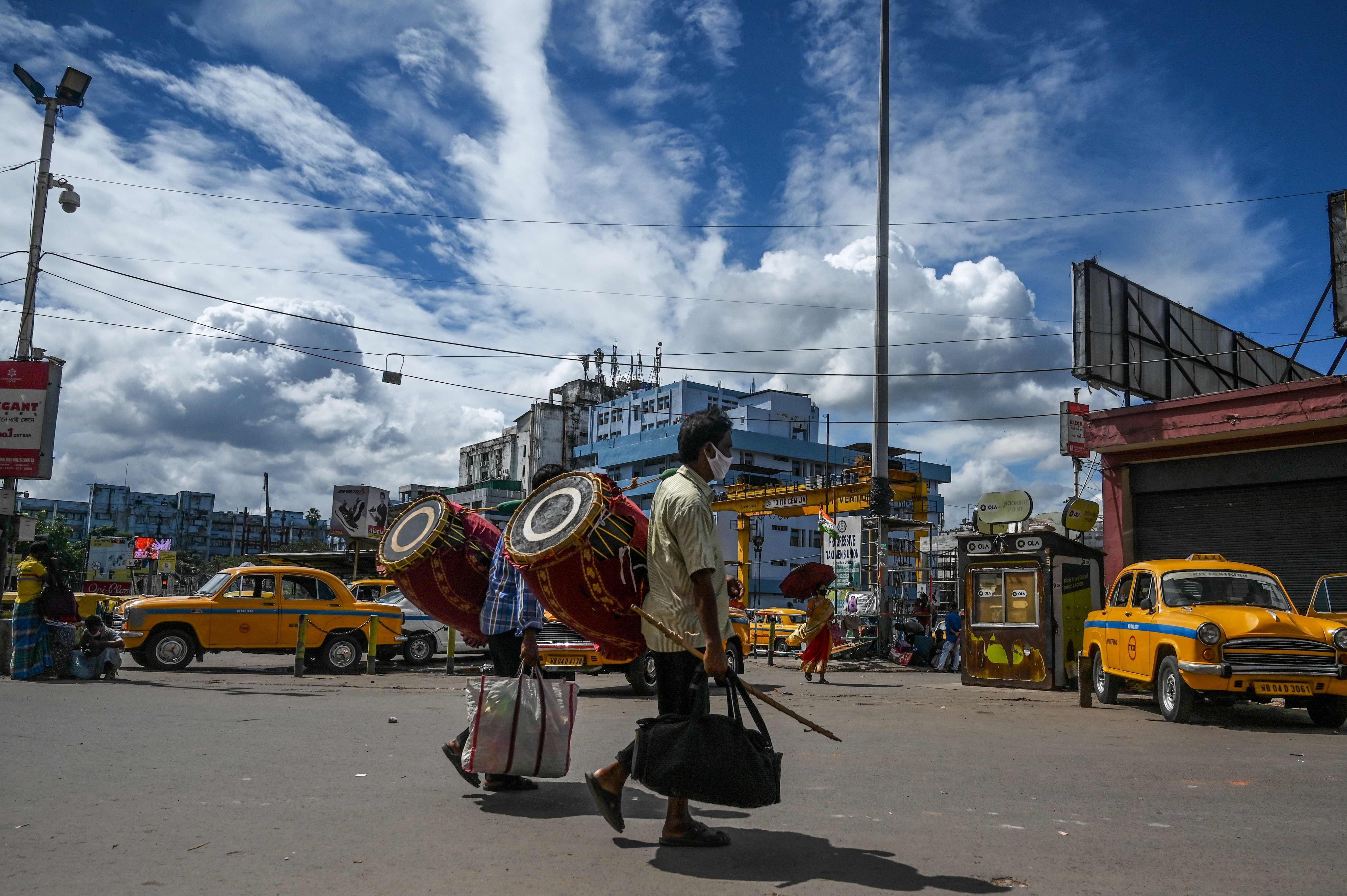 Traditional drummers carrying their drums walk on a street outside the suburban railway station. Credits: AFP Photo