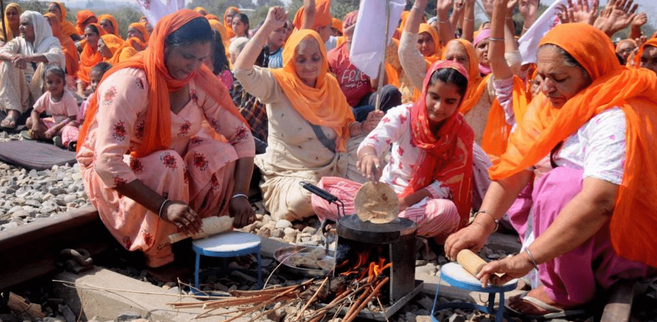 Women prepare 'chapati' as they block a railway track during the ongoing 'Rail Roko' protest over the recent farm reform bills, at Devi Dass Pura village in Amritsar district, Saturday, Oct. 17, 2020. Credit: PTI Photo