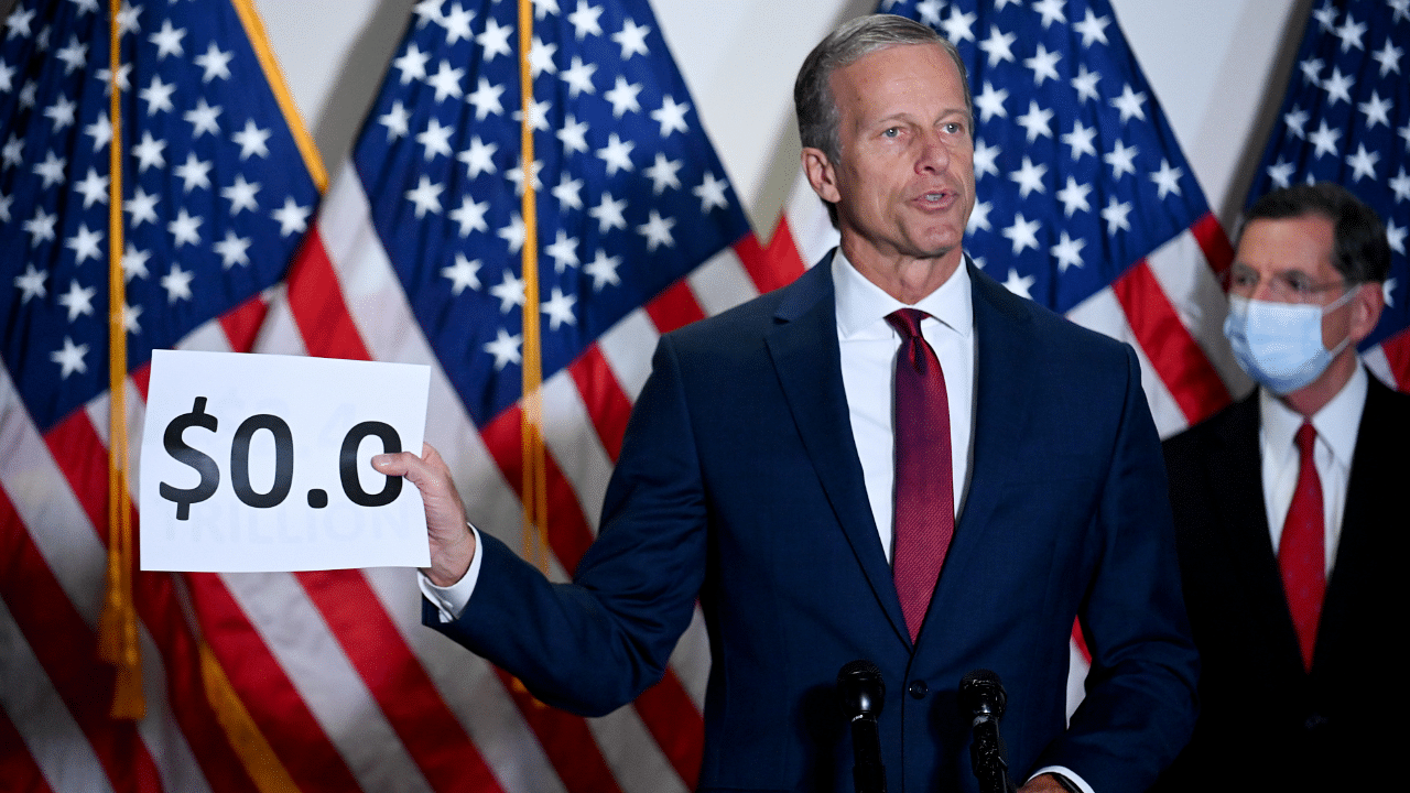 Senator John Thune (R-SD) holds a sign, which refers to the spending for the coronavirus relief bill. Credits: Reuters Photo
