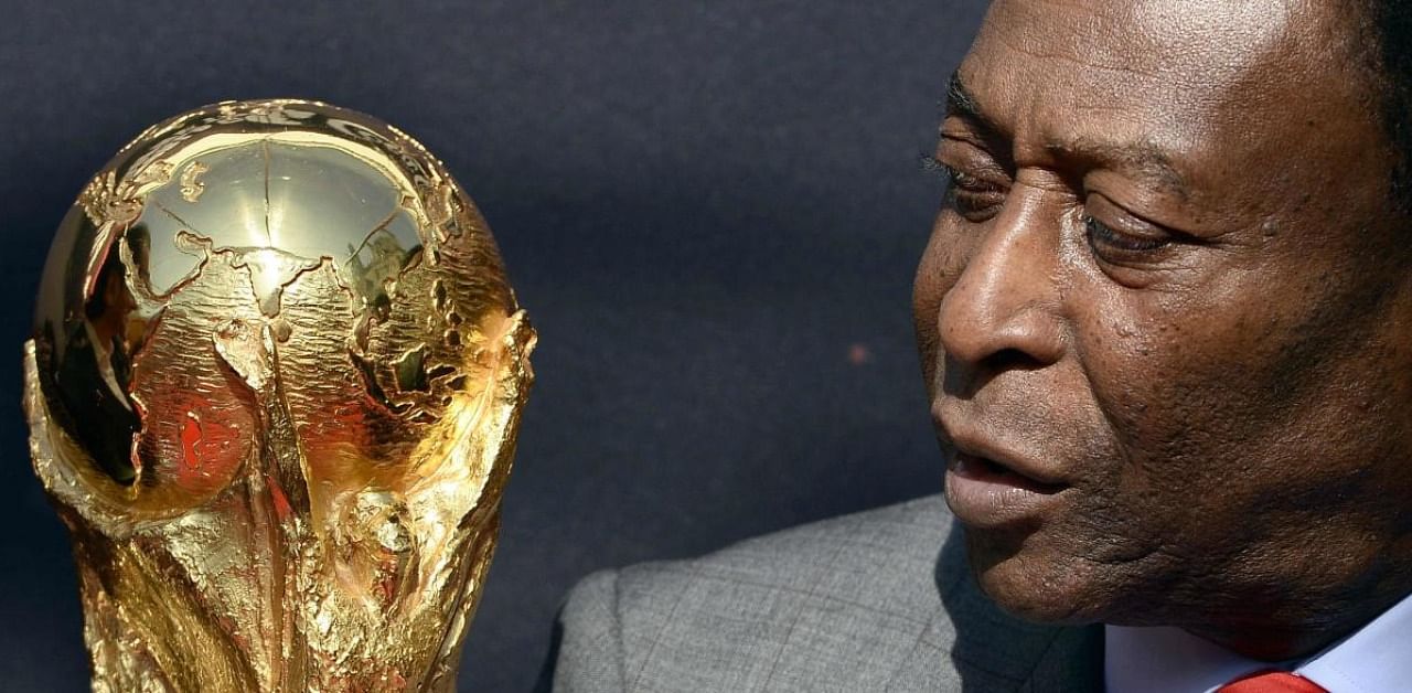 In this file photo taken on March 9, 2014 Brazilian football legend Pele looks at the FIFA World Cup trophy during a FIFA event outside the Hotel de Ville in Paris. Credit: AFP.