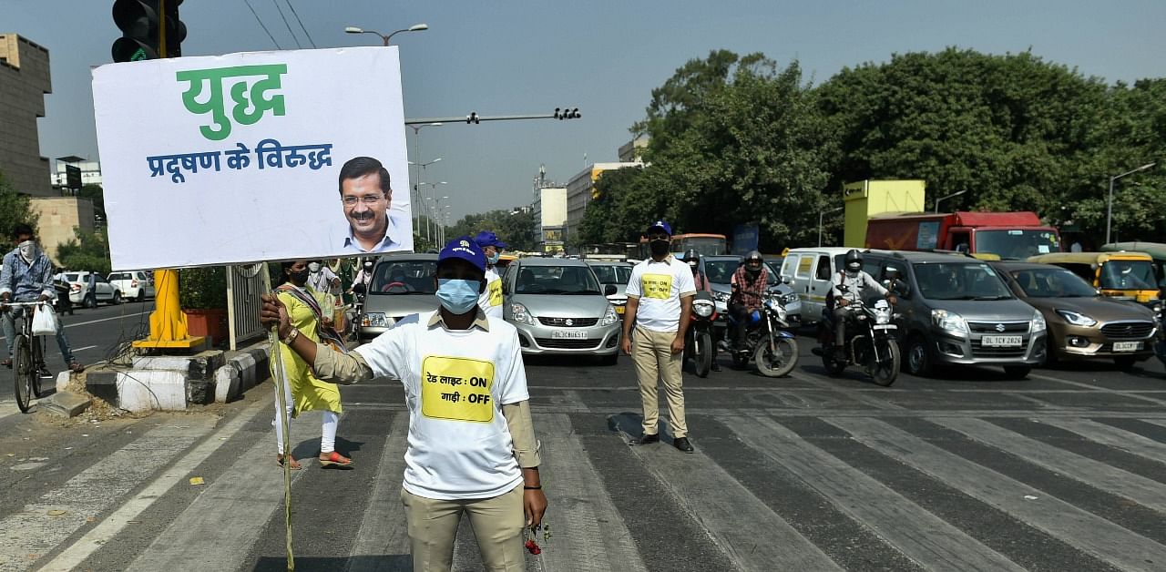 A Civil Defence volunteer holds a placard as he requests commuters to participate in the campaign 'Red Light On, Gaadi Off', launched by Delhi Government to tackle air pollution, in New Delhi. Credit: PTI Photo