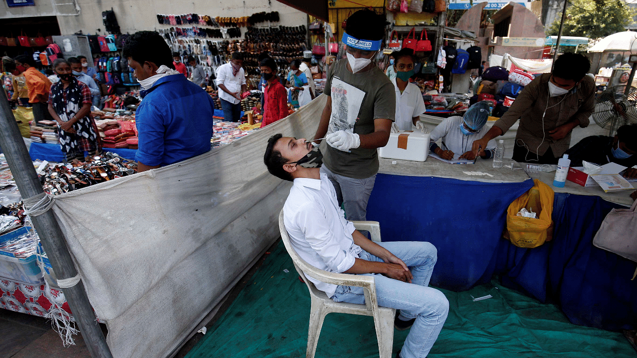 A healthcare worker takes swab from a man for a rapid antigen test in a market area, amidst the Covid-19 pandemic. Credits: Reuters Photo