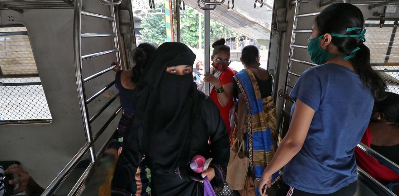 Women wearing protective face masks board a suburban train after authorities resumed the train services for women passengers during non-peak hours, amidst the coronavirus disease outbreak in Mumbai. Credit: Reuters.