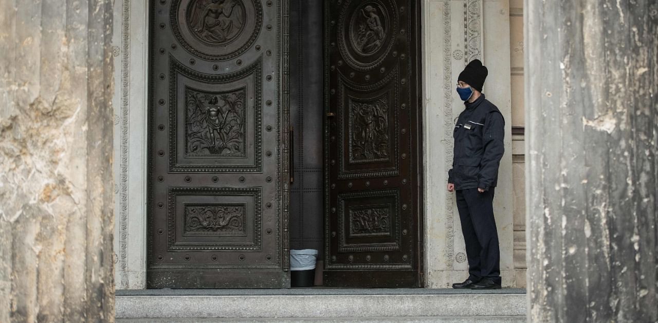 An employee with a protective face mask stands at the entrance of the Neues Museum, part of the Museum Island, in Berlin. Credit: AFP