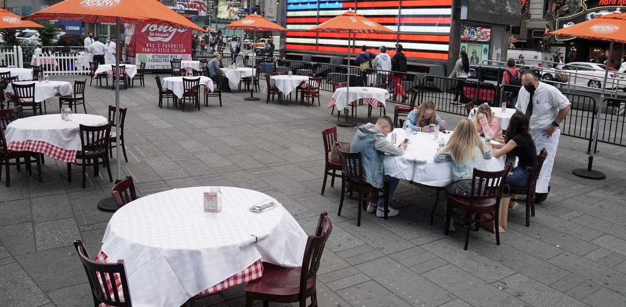 A server talks to a table of guests at a pop up restaurant set up in Times Square for 'Taste of Times Square Week' during the coronavirus disease pandemic in the Manhattan borough of New York City. Credit: Reuters.