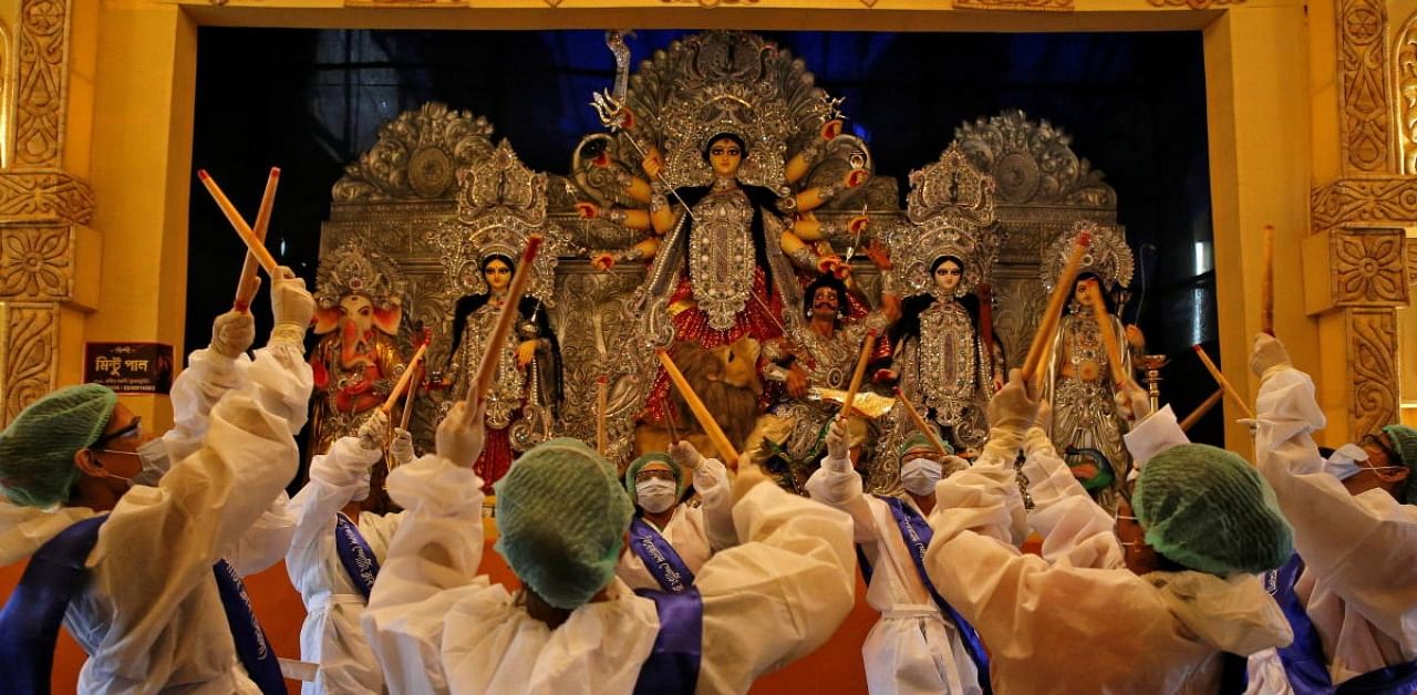 Hindu devotees wearing personal protective equipment perform Dandiya, a traditional dance, in front of an idol of Hindu goddess Durga at a "pandal" or a temporary platform, on the first day of Durga Puja festival in Kolkata, India, October 22, 2020. Credit: Reuters Photo