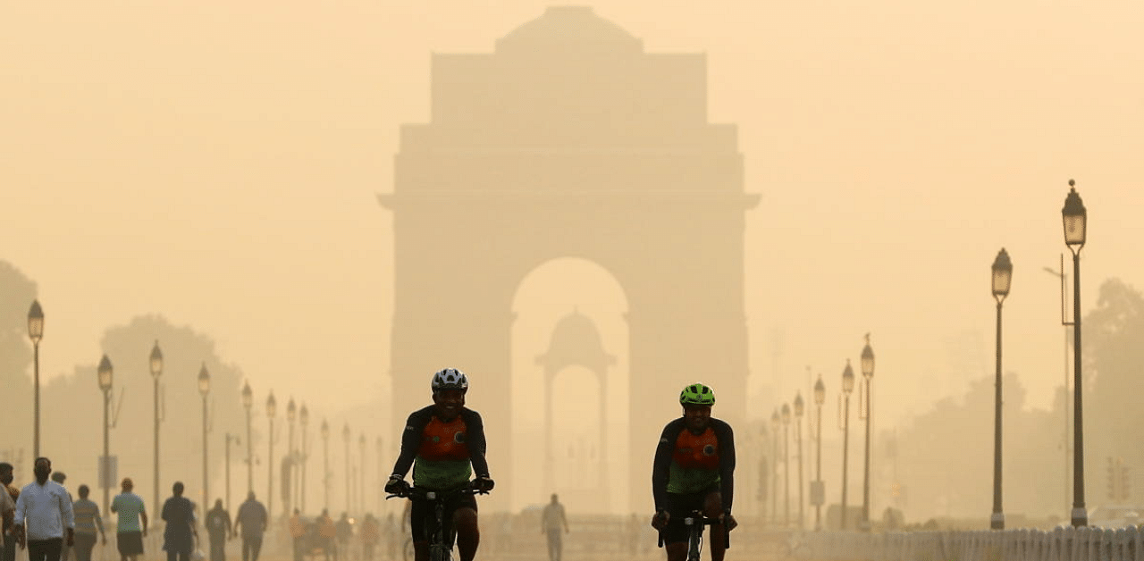 Men ride their bicycles in front of the India Gate shrouded in smog, in New Delhi. Credit: Reuters Photo