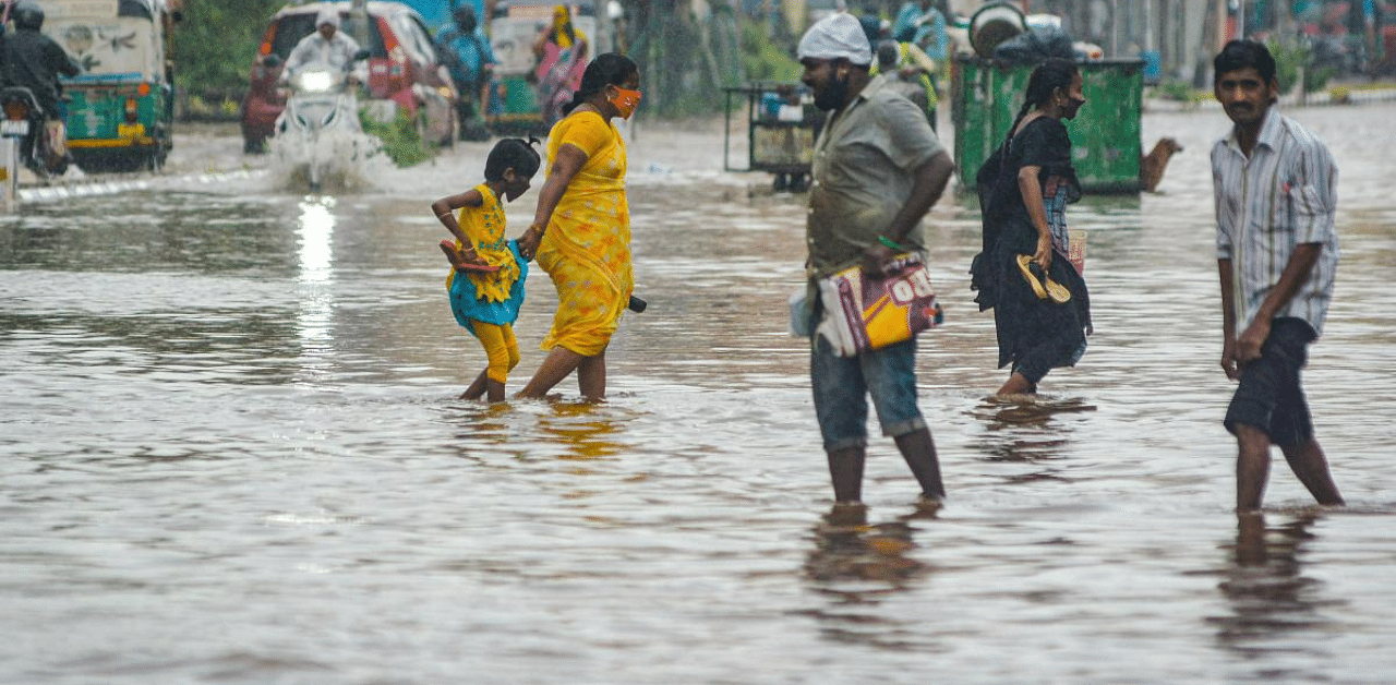  People wade through a waterlogged road during heavy rains, due to a deep depression in Bay of Bengal, in Vijayawada. Credit: PTI File Photo
