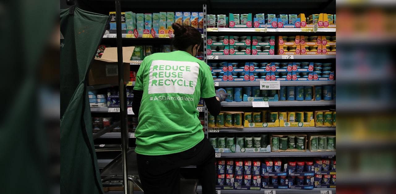 A member of staff stacks loose tins on the shelves in a UK supermarket. Credit: Reuters