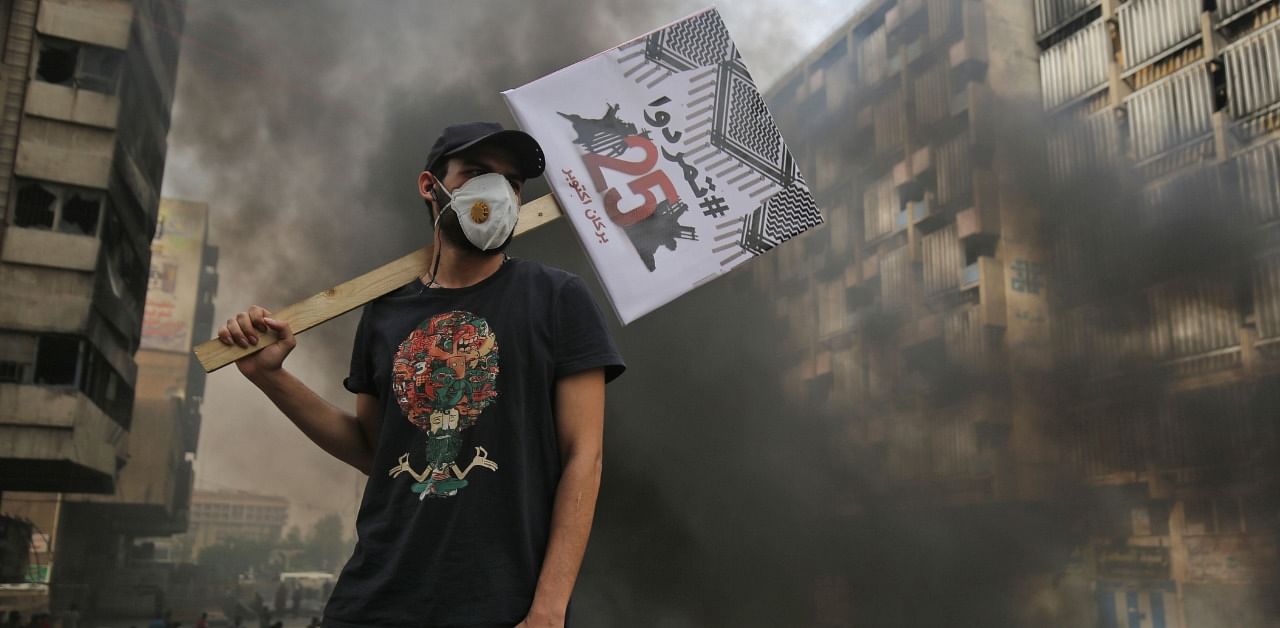 An Iraqi protester carries a placard reading in Arabic "Revolt" during a demonstration on the Sinak bridge in the capital Baghdad. Credit: AFP