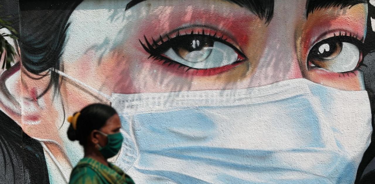 A woman walks past a graffiti of a girl wearing a protective mask amidst the spread of the coronavirus disease (Covid-19) in Mumbai, India, October 23, 2020. Credit: Reuters Photo