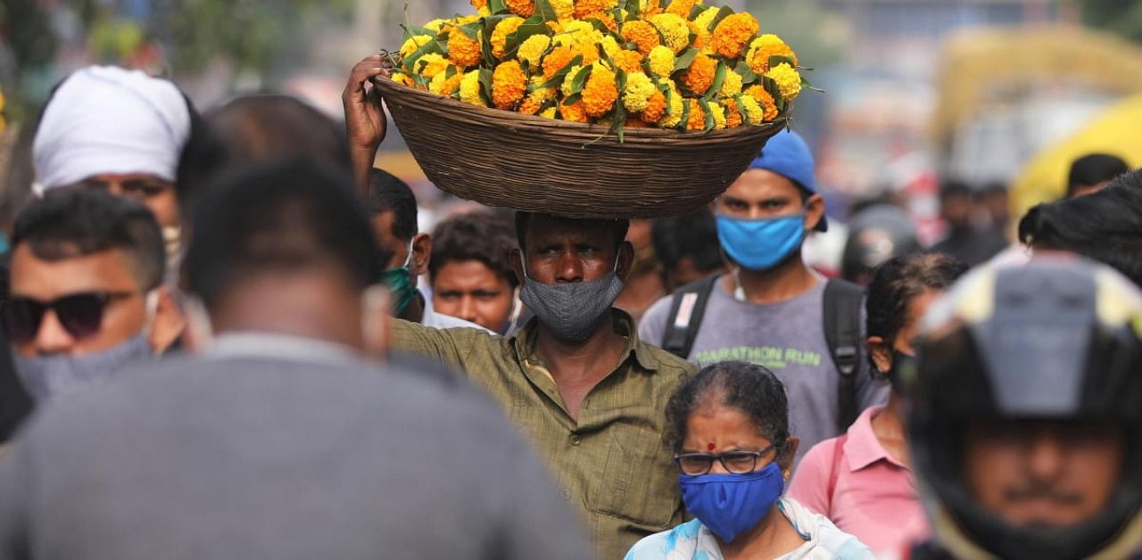 A man carrying flowers walks in a crowded market a day before the Hindu festival of Dussehra amidst the spread of the coronavirus disease (Covid-19) in Mumbai, India, October 24, 2020. Credit: Reuters Photo