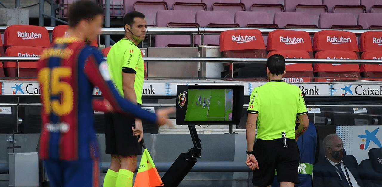 Spanish referee Juan Martinez Munuera (R) reviews the VAR for a penalty check during the Spanish League football match between Barcelona and Real Madrid at the Camp Nou stadium in Barcelona. Credit: AFP Photo
