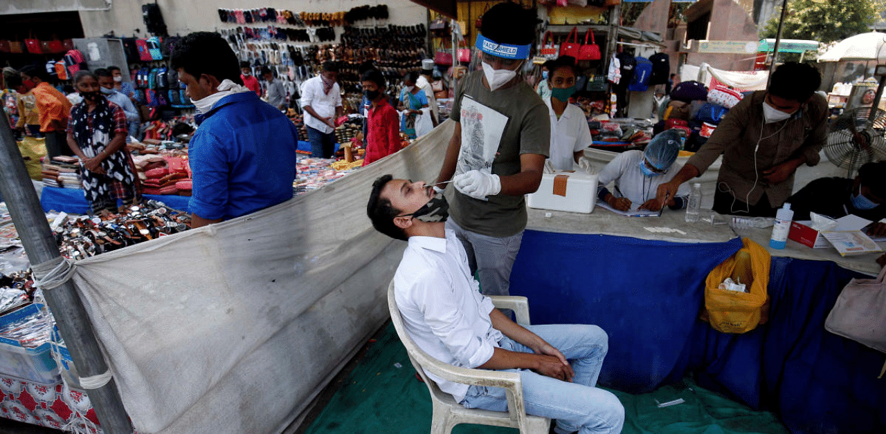 A healthcare worker takes swab from a man for a rapid antigen test in a market area, amidst the Covid-19 pandemic in Ahmedabad. Credit: Reuters Photo