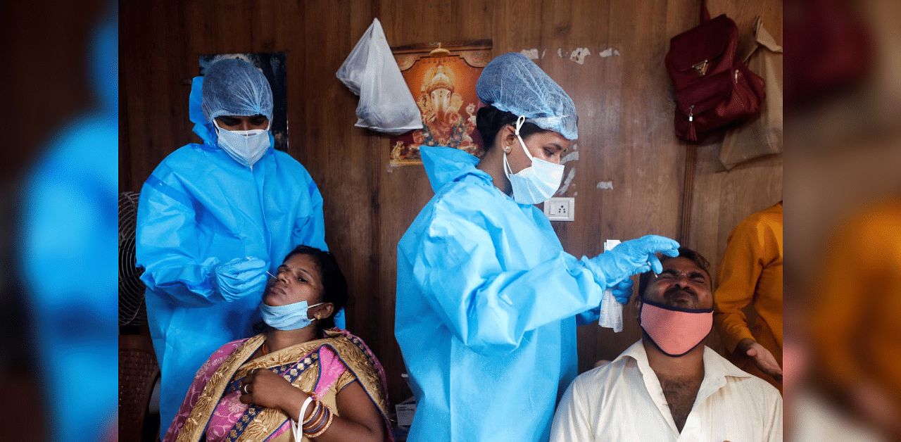 Health workers in personal protective equipment (PPE) collect swab samples from migrants who returned from their hometown at a railway station during a rapid antigen testing campaign for the coronavirus disease, on the outskirts of Mumbai, India, October, 3, 2020. Credit: Reuters Photo